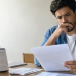 Cena ilustrativa de descontos e créditos bancários: funcionário brasileiro observando holerite em branco e extrato abstrato ao lado de calendário doméstico sem números legíveis