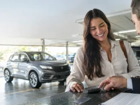 Cena ilustrativa de aluguel de veículos e cartão: carro alugado genérico em estacionamento iluminado, chave sobre balcão de locadora e cartão sem marca ao lado de contrato ilegível