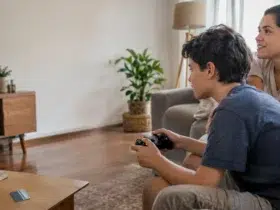 Cena ilustrativa de jogos digitais e cobranças: mãe e filho em sofá de casa brasileira, controle de videogame sem marca e cartão genérico sobre mesa, televisão sem conteúdo legível